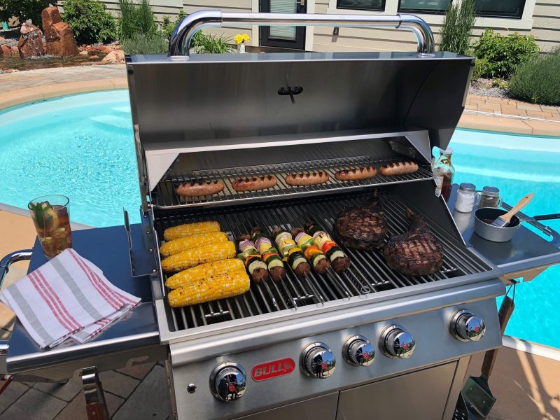 outdoor barbeque grill with corn, hot dogs, steak and kabobs